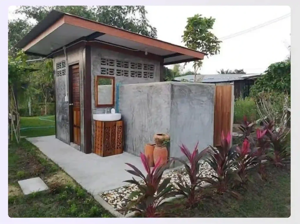 A rustic concrete outhouse with an outdoor sink