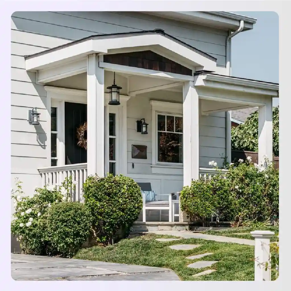 Craftsman-style porch with bushes and a small bench