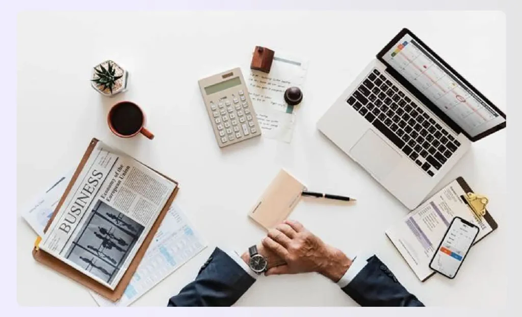 Designer's desk with laptop, calculator, and contract papers