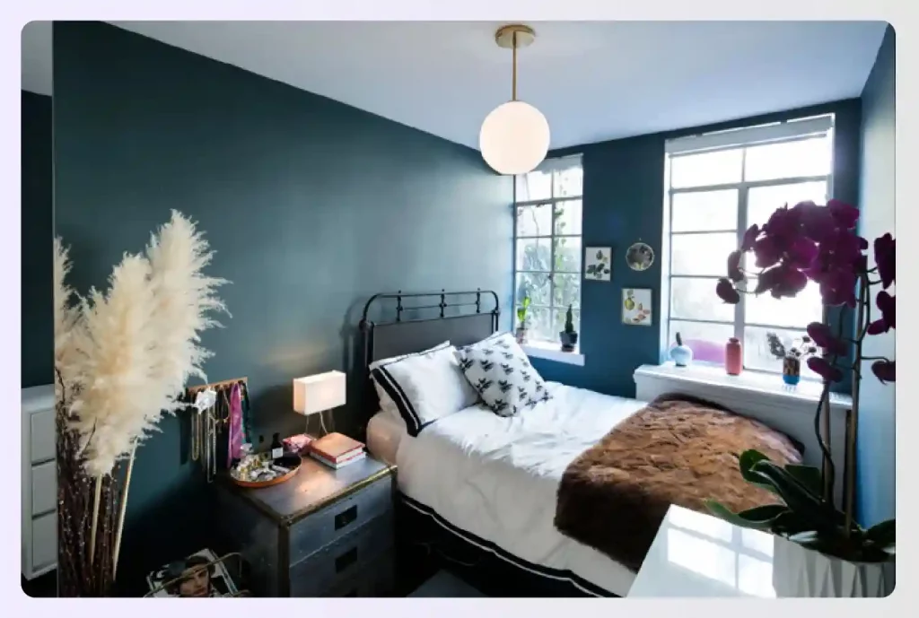 A bedroom with dark teal walls and light bedding