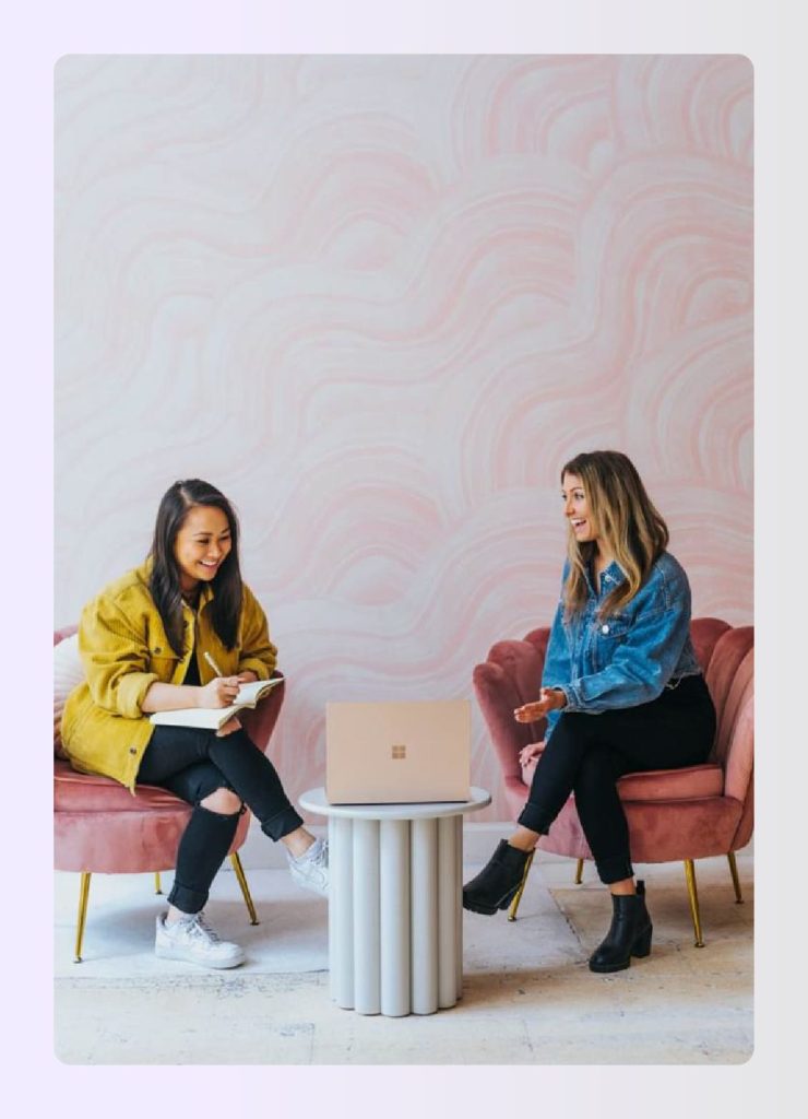 Two women discussing notes in a pink room Two women discussing notes in a pink room