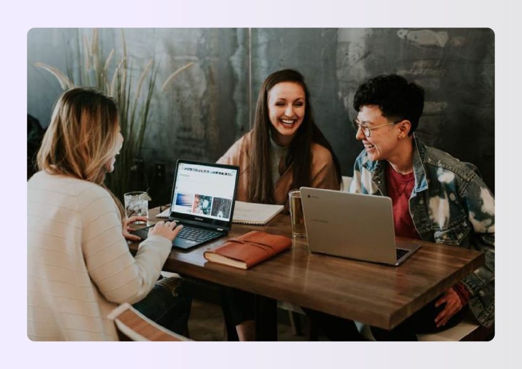 Three colleagues laughing while working on laptop