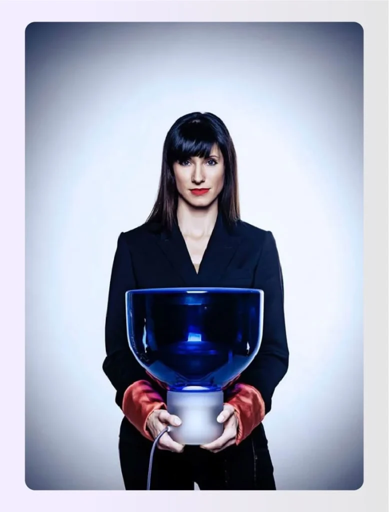 Lucie Koldova holding a large blue glass light fixture Lucie Koldova holding a large blue glass light fixture