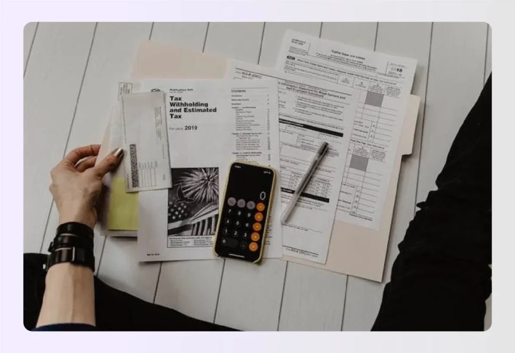 Person calculating taxes and reviewing financial documentsย Person calculating taxes and reviewing financial documentsย