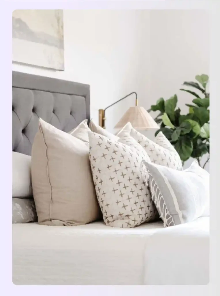 Bed styled with beige, patterned, and textured throw pillows Bed styled with beige, patterned, and textured throw pillows