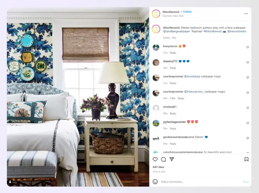 A bedroom with bold, blue floral patterned wallpaper