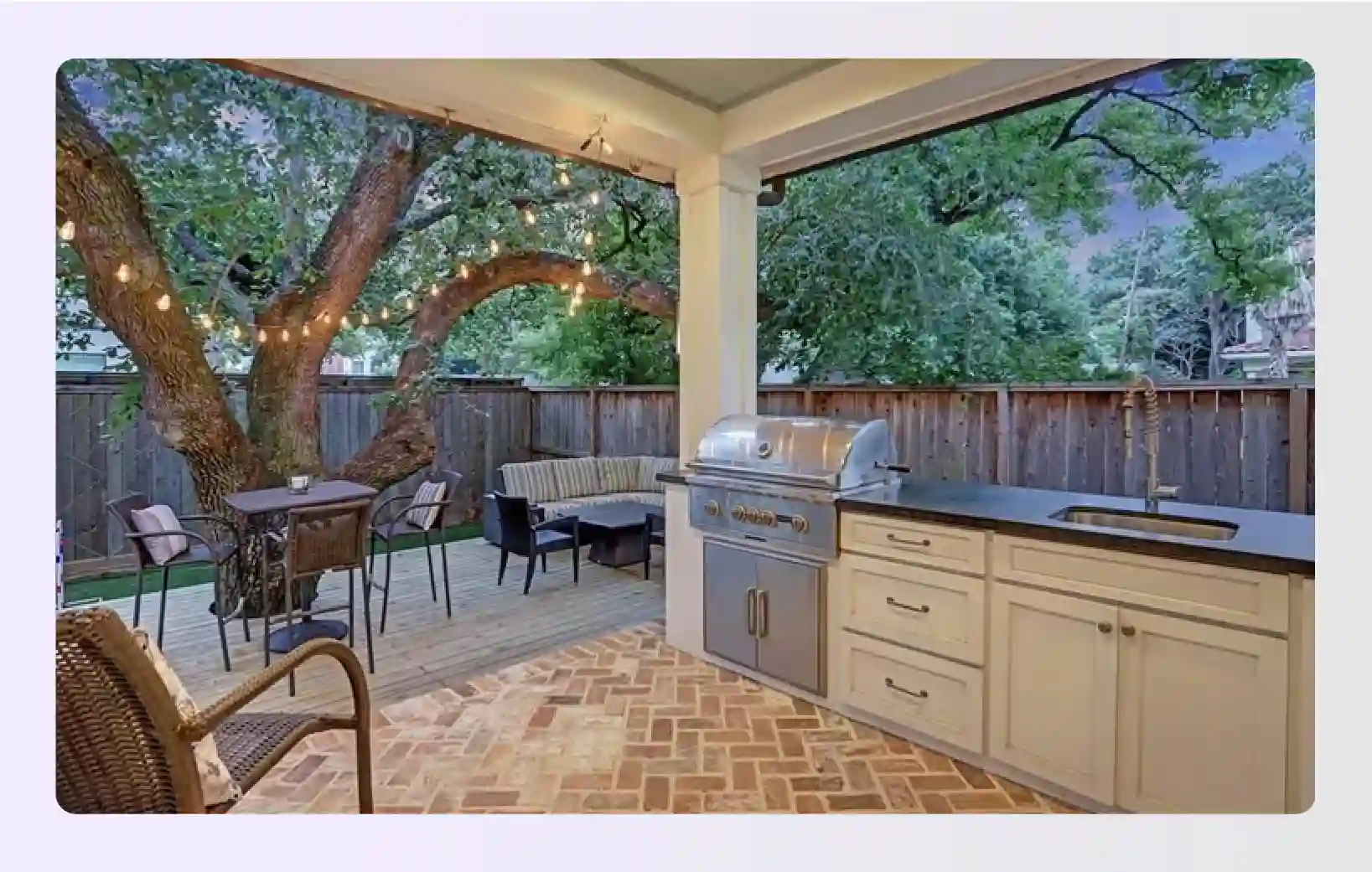 Covered patio kitchen with white cabinets and a large tree nearby Covered patio kitchen with white cabinets and a large tree nearby