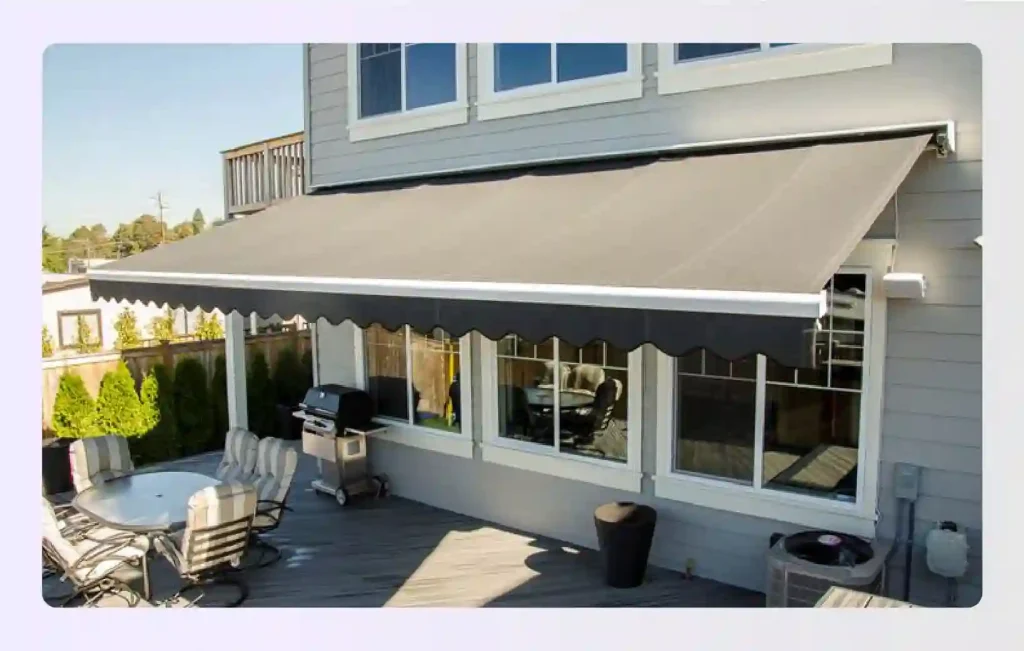Retractable black awning shading a deck with grill station