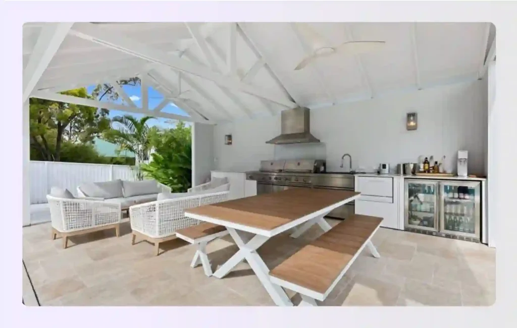 White coastal style outdoor kitchen with vaulted ceiling and fans
