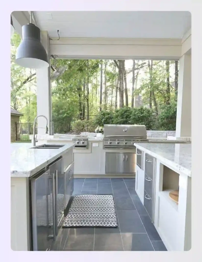 Compact white outdoor kitchen with stainless steel appliances and pendant lights Compact white outdoor kitchen with stainless steel appliances and pendant lights