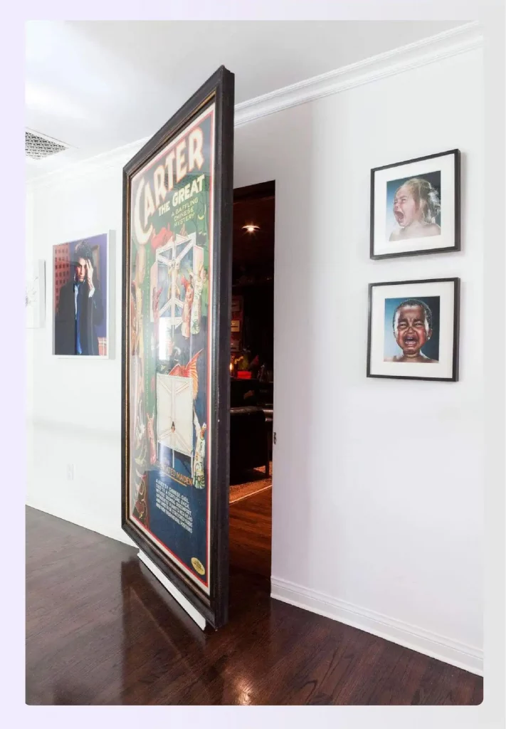 A large framed art poster acting as a hidden pivot door