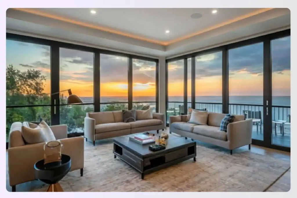 A living room with large windows showing a beautiful sunset