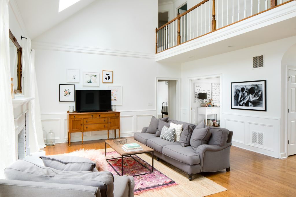 A bright and airy living room with white walls, hardwood floors, and a cozy sofa and armchair.