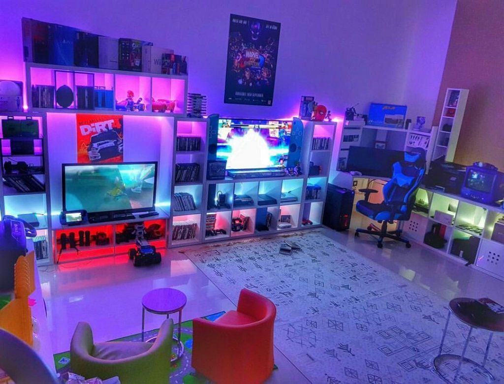A bright and colorful gaming room with a large TV, a gaming PC, and a comfortable chair.
