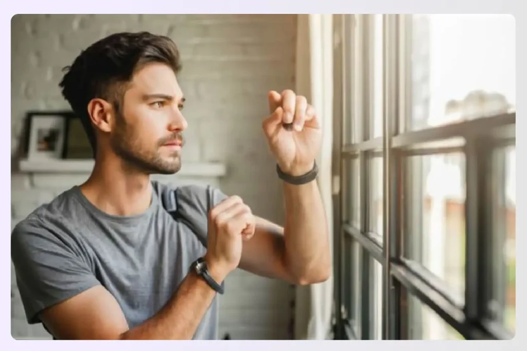 Man adjusting his smartwatch with a window in background