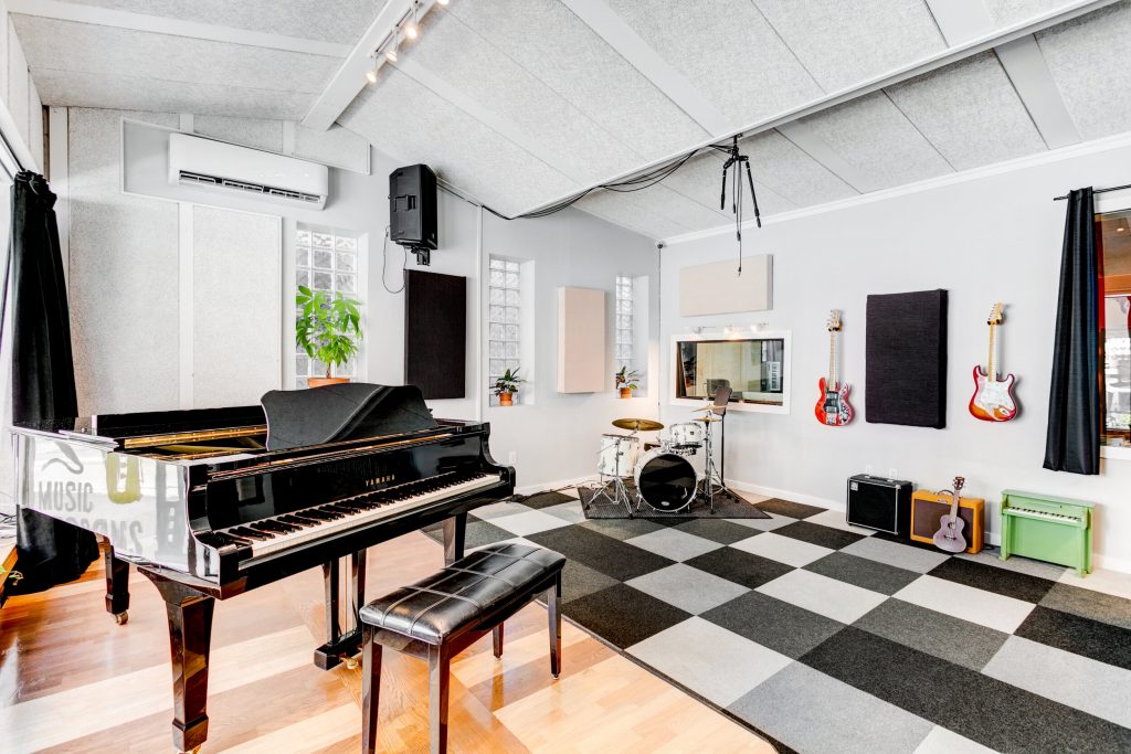 Music room with a grand piano, drums, guitars, and other instruments.