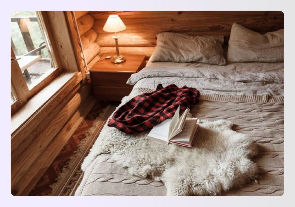 Plaid shirt and open book on a rustic knit blanket.