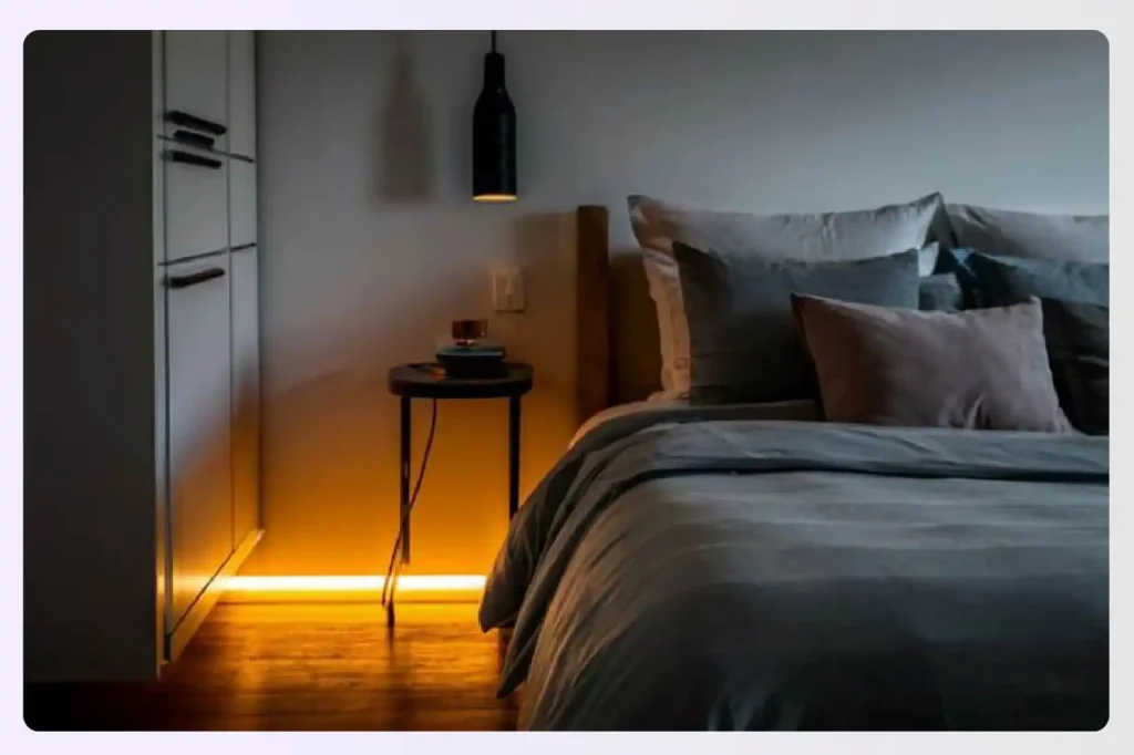 Warm LED light strip glowing under a modern bed