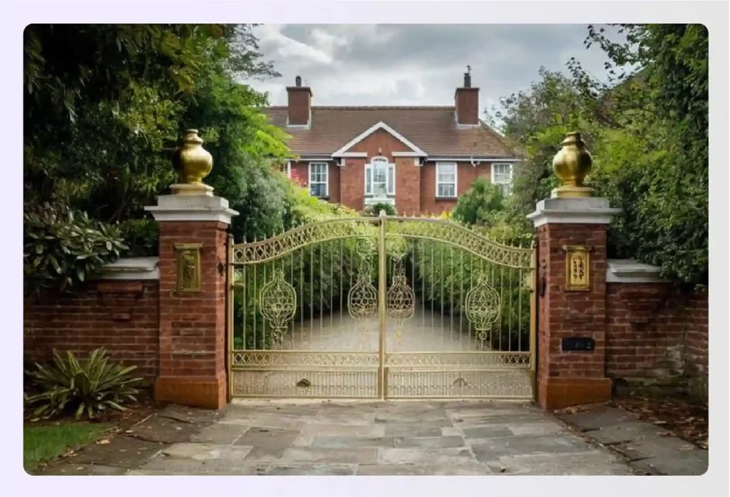 Ornate golden metal gates in front of a brick house