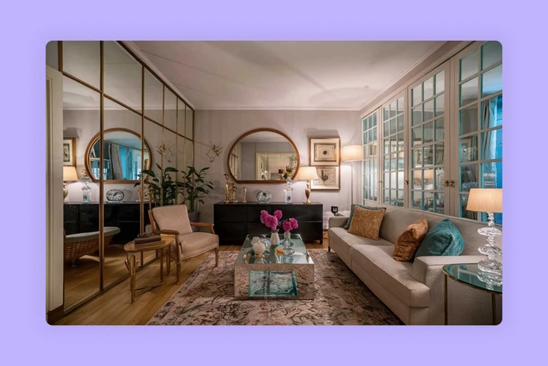 A bright living room furnished with a sofa, armchair, coffee table, and wall mirrors.