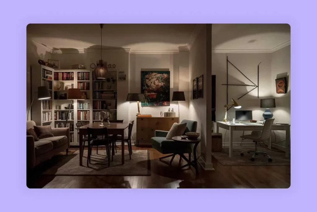 A brightly lit living room with a comfortable couch, a coffee table, two chairs for seating, and a desk in the corner with a bookshelf beside it.
