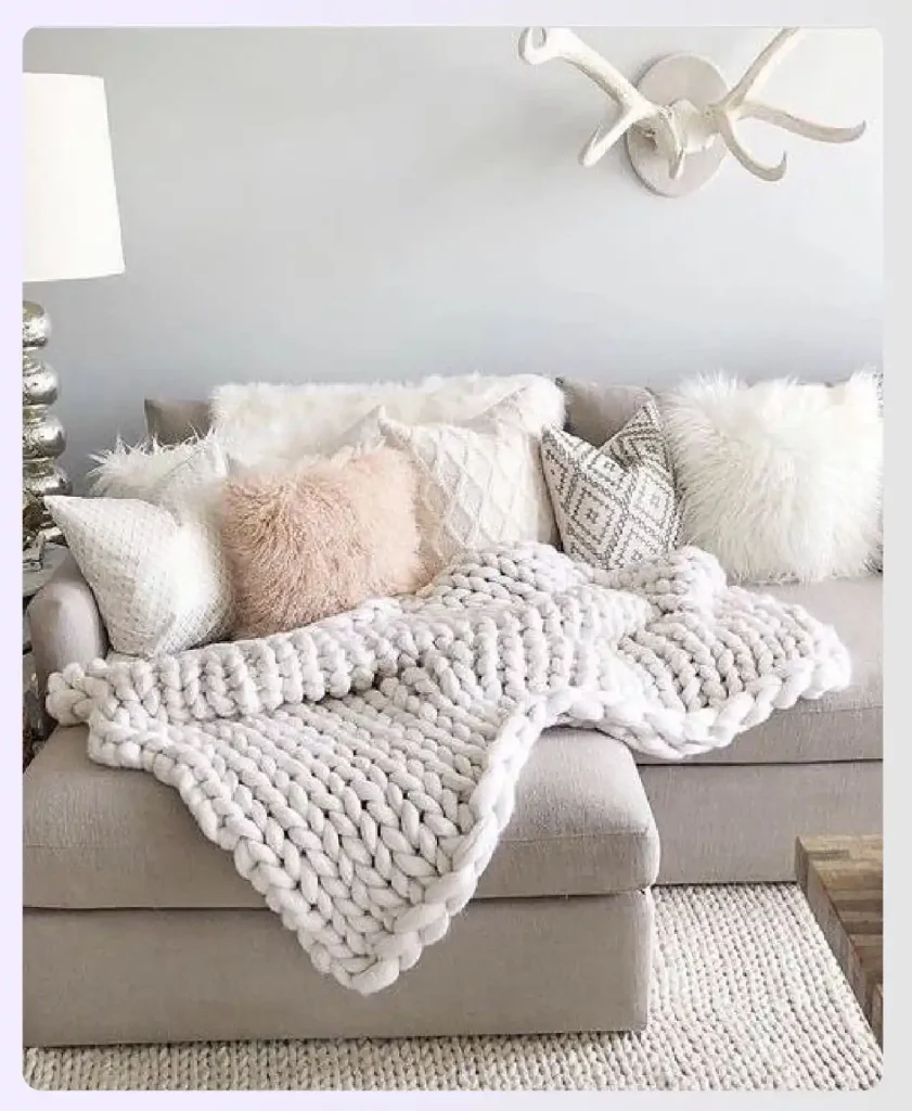 Textured throw pillows and a knit blanket on a sofa