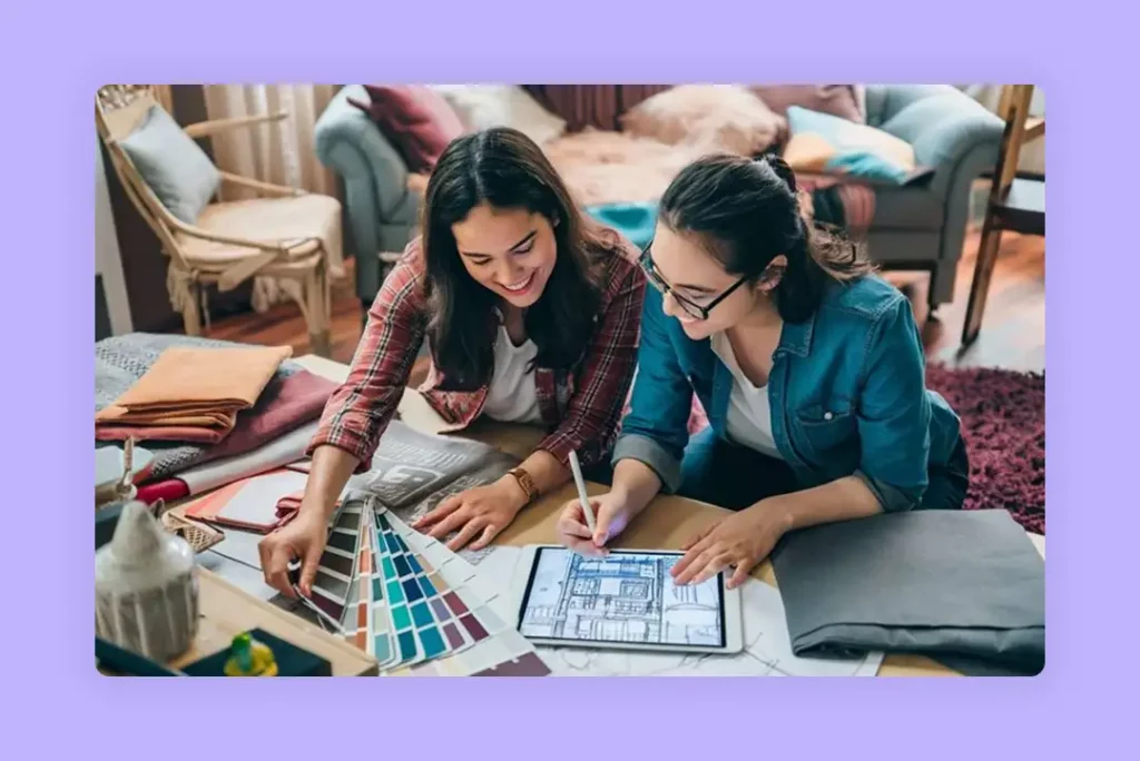 Two female interior designers collaborating on a project using color swatches and a tab.
