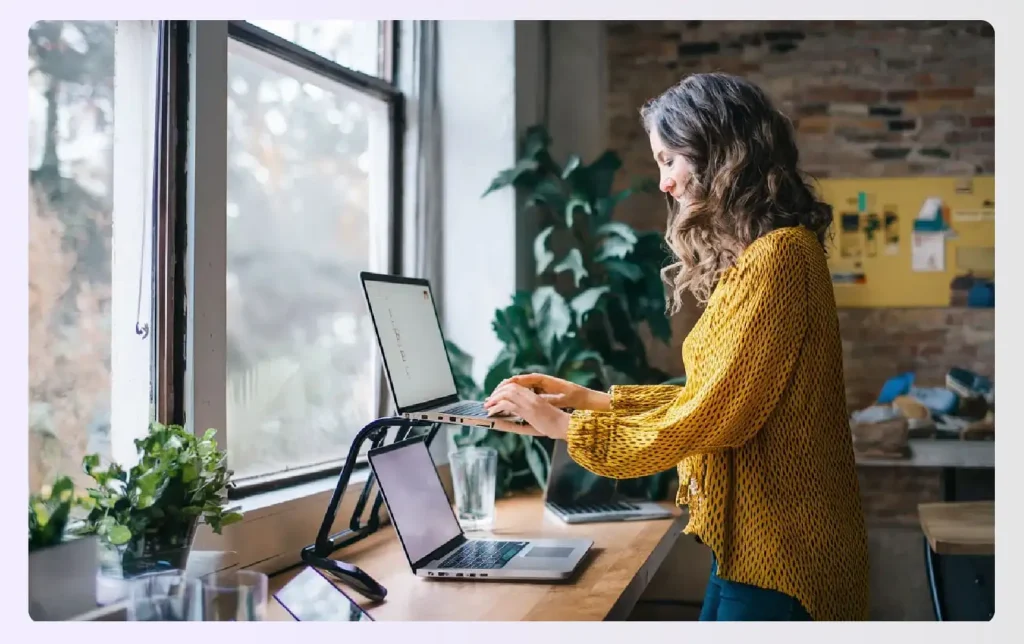 A woman using a laptop stand on her desk A woman using a laptop stand on her desk